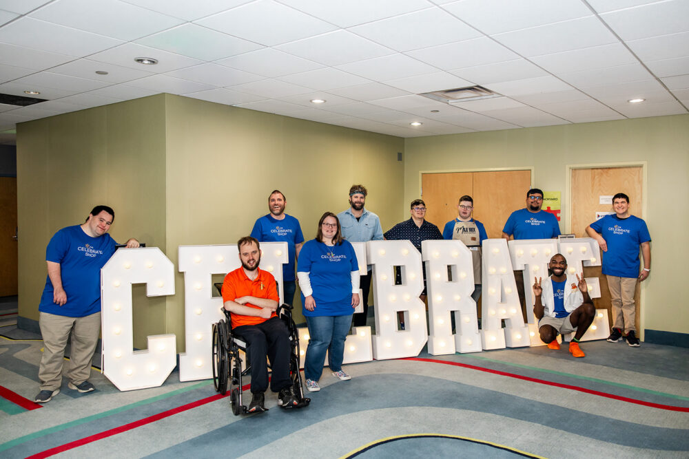 Group of entrepreneurs with disabilities at The Celebrate Shop in front of big white letters spelling Celebrate